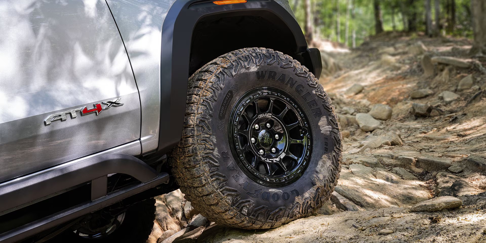 Close-up view of the GMC Canyon AT4 tires while off-roading on a rocky path.