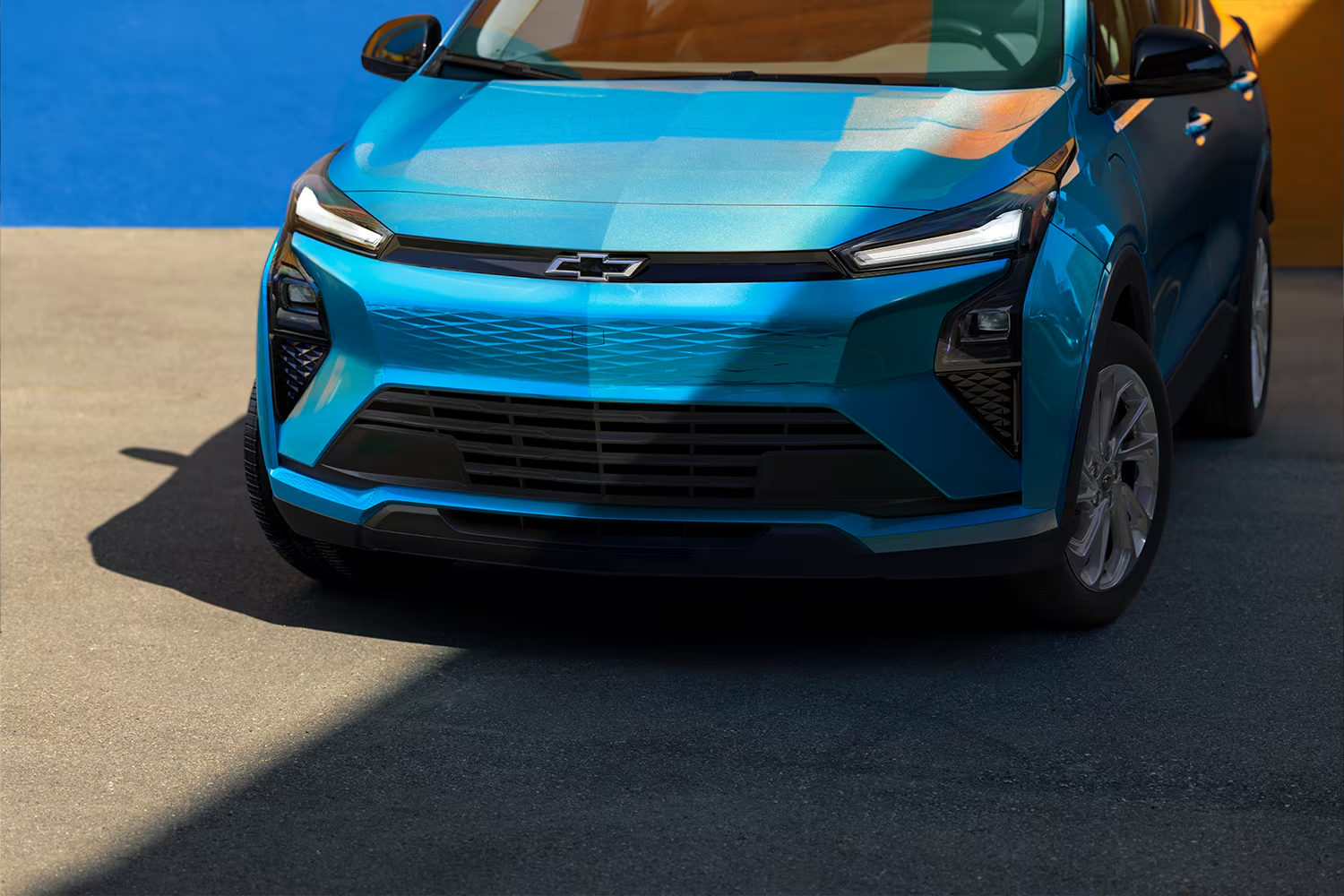 A Front View Close-Up of a Light Blue 2027 Chevrolet Bolt, Highlighting the New Front Fascia, Black Grille, and Prominent Chevrolet Bowtie Logo in the Center.